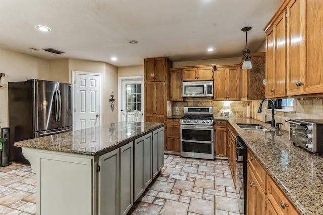 kitchen with a center island, dark stone counters, sink, decorative backsplash, and appliances with stainless steel finishes