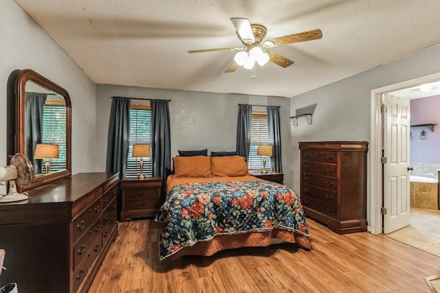 bedroom featuring ceiling fan, light hardwood / wood-style floors, a textured ceiling, and connected bathroom