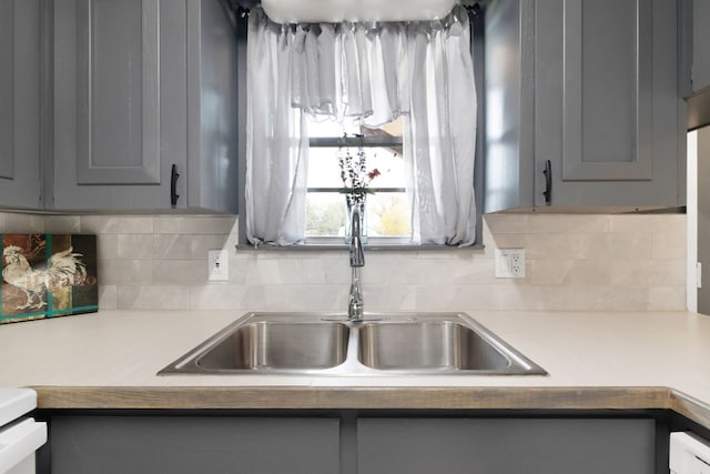 kitchen featuring backsplash, gray cabinetry, and sink