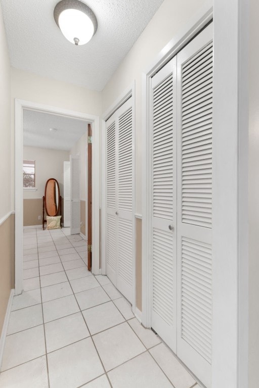 hall with light tile patterned floors and a textured ceiling