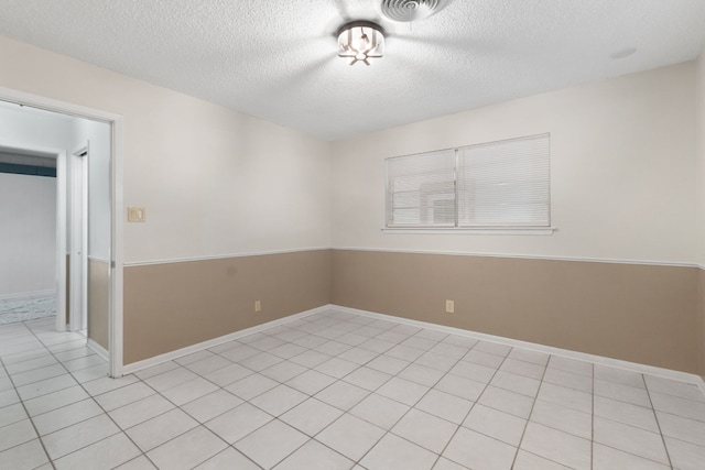 tiled spare room featuring a textured ceiling