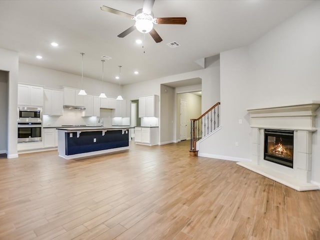 unfurnished living room featuring ceiling fan and light hardwood / wood-style flooring