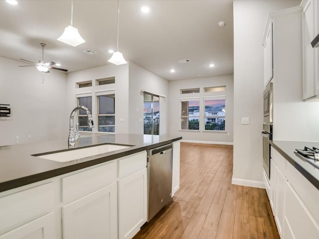 kitchen with sink, hanging light fixtures, light wood-type flooring, white cabinetry, and stainless steel appliances