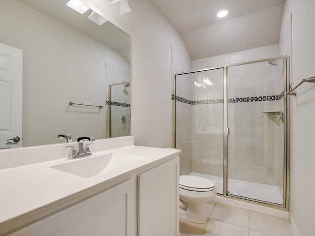 bathroom featuring tile patterned floors, vanity, a shower with shower door, and toilet