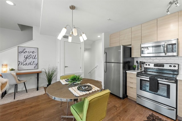 kitchen featuring pendant lighting, decorative backsplash, light brown cabinets, and stainless steel appliances