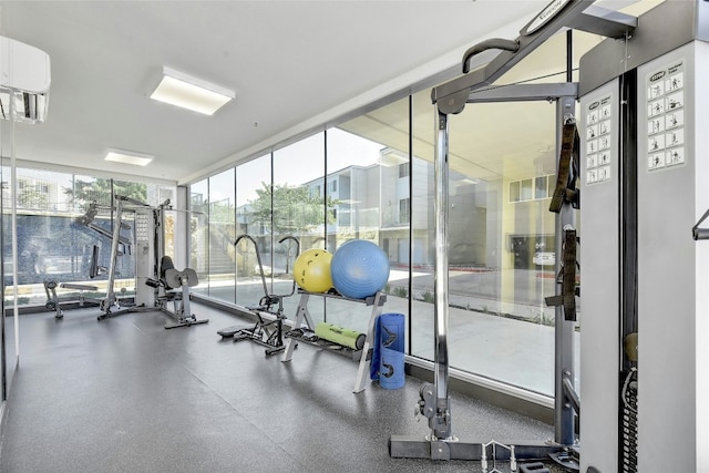 gym featuring a wall mounted air conditioner, floor to ceiling windows, and a healthy amount of sunlight