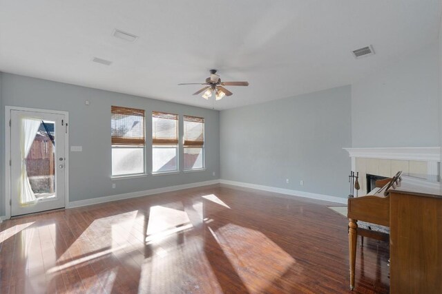 unfurnished living room with a tile fireplace, ceiling fan, and hardwood / wood-style floors