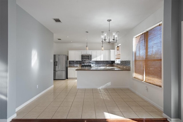 kitchen with kitchen peninsula, stainless steel appliances, light tile patterned floors, white cabinetry, and hanging light fixtures