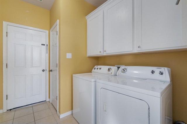 clothes washing area featuring washer and clothes dryer, light tile patterned floors, and cabinets