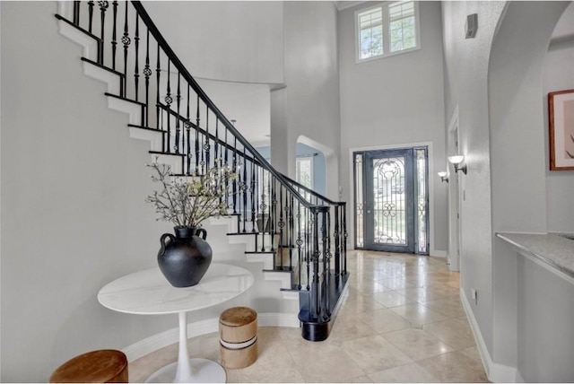 foyer with a towering ceiling and light tile patterned floors