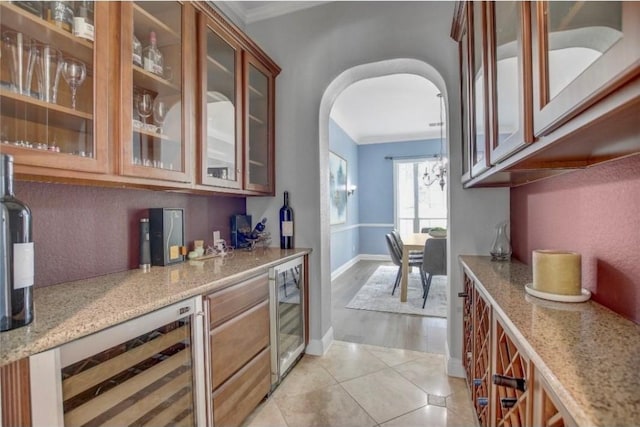 bar with light stone countertops, light tile patterned floors, beverage cooler, and crown molding