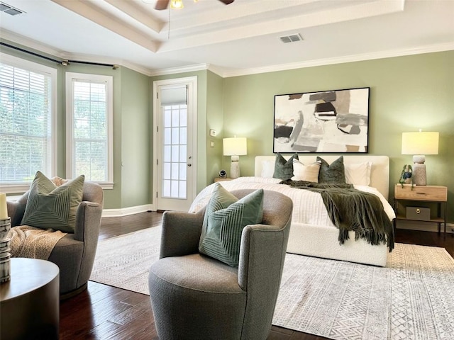 bedroom featuring ceiling fan, ornamental molding, dark wood-type flooring, and a tray ceiling