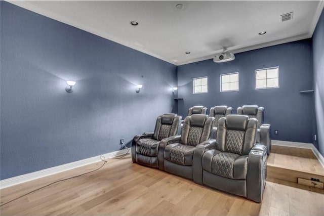 home theater room with ornamental molding and light hardwood / wood-style flooring