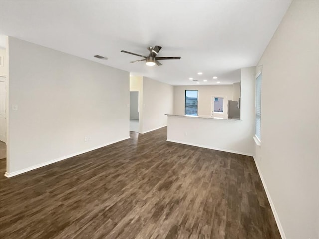 unfurnished living room with ceiling fan and dark wood-type flooring