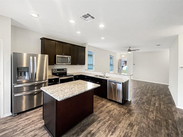 kitchen featuring dark brown cabinets, stainless steel appliances, ceiling fan, sink, and a center island