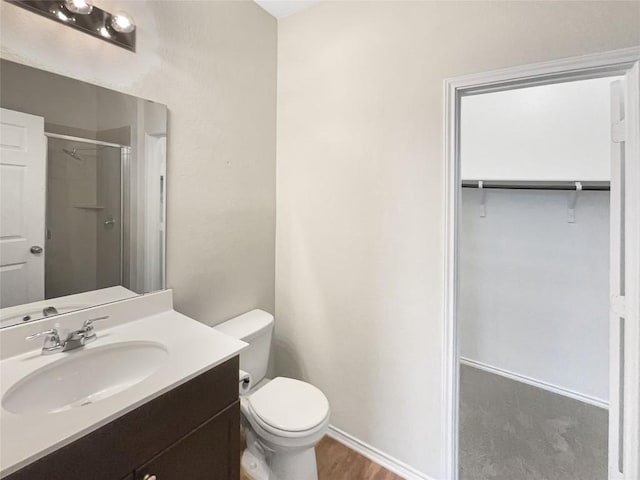 bathroom featuring hardwood / wood-style flooring, vanity, a shower with shower door, and toilet