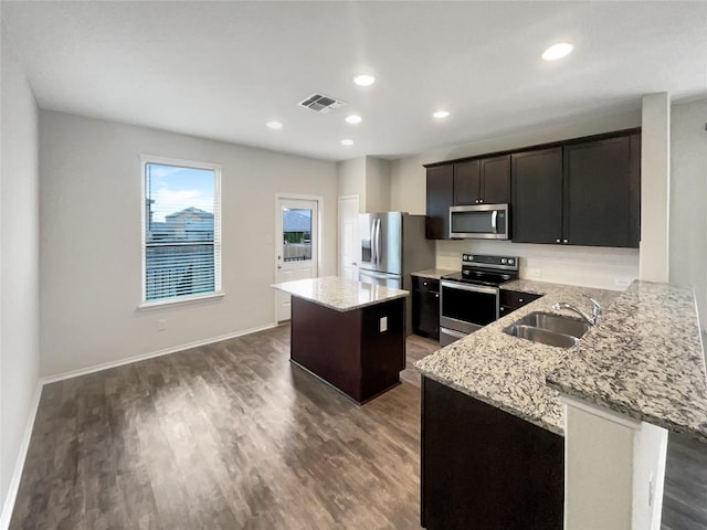 kitchen featuring sink, a kitchen island, light stone counters, kitchen peninsula, and stainless steel appliances