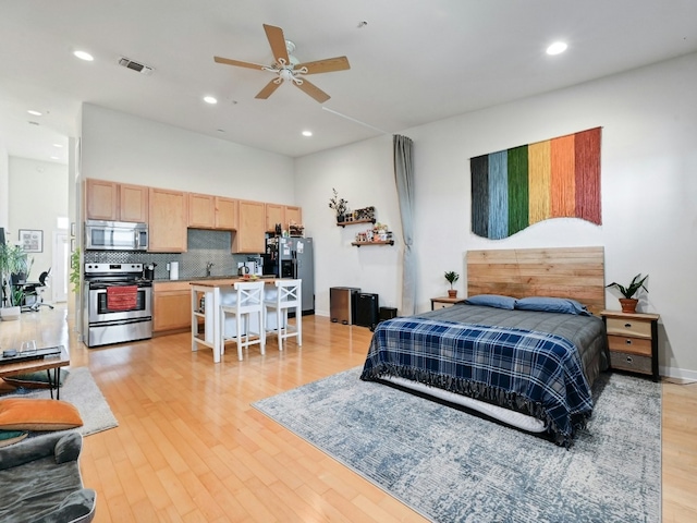 bedroom with ceiling fan, light hardwood / wood-style floors, stainless steel fridge with ice dispenser, and sink