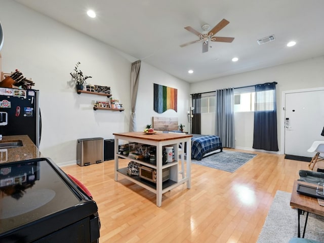 interior space featuring ceiling fan, black refrigerator, and light wood-type flooring