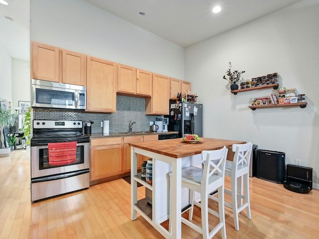 kitchen with butcher block countertops, light brown cabinetry, and stainless steel appliances