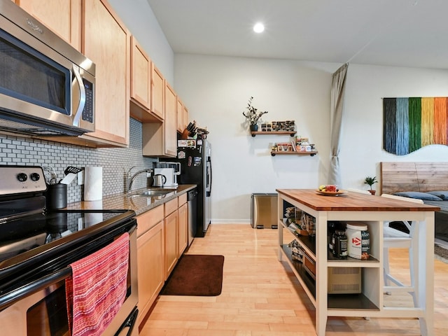 kitchen with appliances with stainless steel finishes, tasteful backsplash, sink, light brown cabinets, and light hardwood / wood-style floors