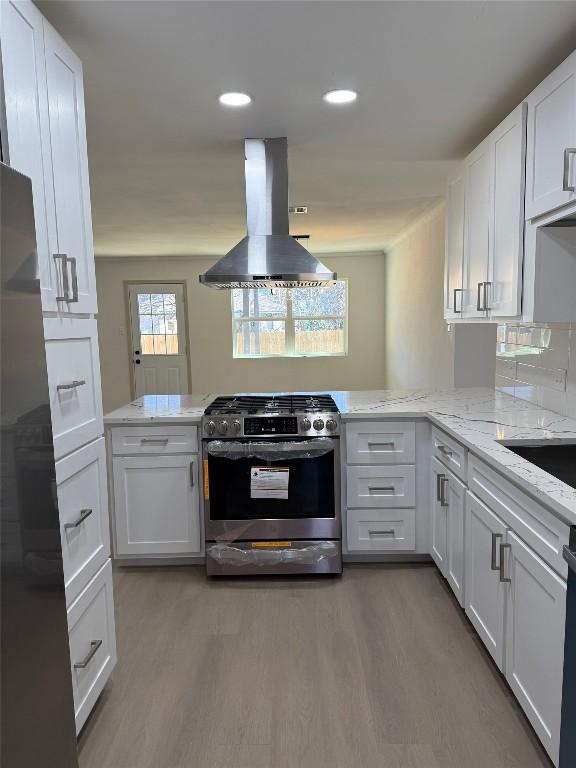 kitchen featuring kitchen peninsula, island range hood, white cabinets, and stainless steel appliances