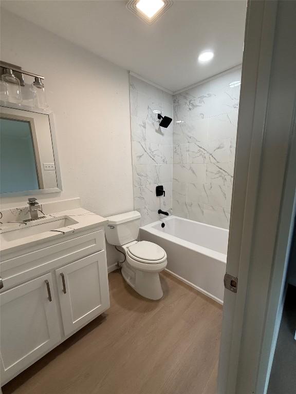 full bathroom with vanity, hardwood / wood-style floors, tiled shower / bath combo, and toilet