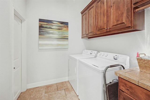 clothes washing area with washer and clothes dryer, light tile patterned flooring, and cabinets