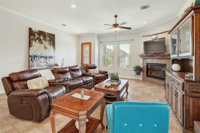 living room featuring ceiling fan, ornamental molding, and a tiled fireplace