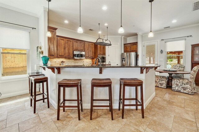 kitchen with pendant lighting, decorative backsplash, dark stone countertops, a kitchen bar, and stainless steel appliances