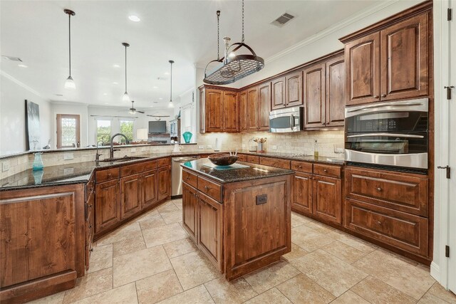 kitchen featuring a center island, sink, hanging light fixtures, stainless steel appliances, and kitchen peninsula