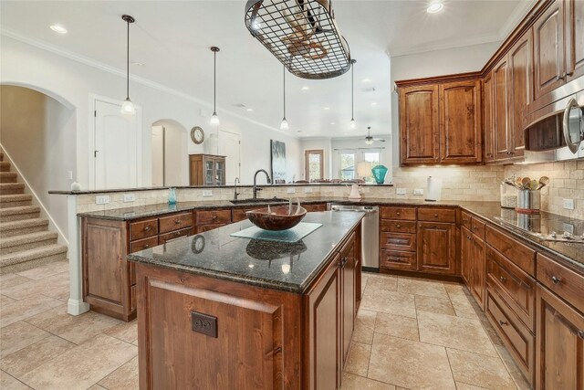 kitchen with kitchen peninsula, stainless steel appliances, ceiling fan, decorative light fixtures, and a kitchen island