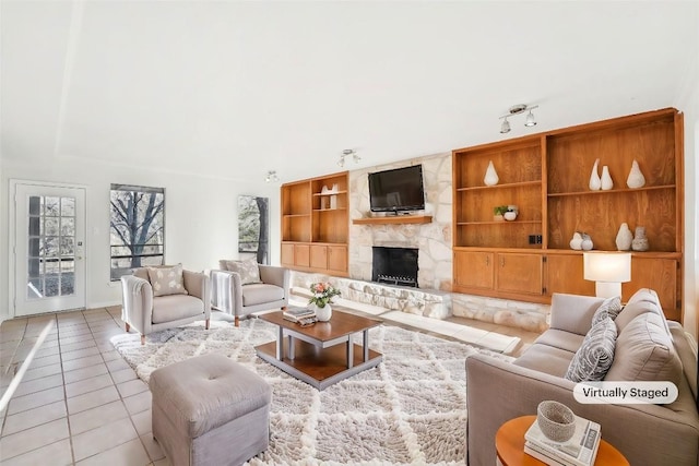 tiled living room featuring built in shelves and a stone fireplace