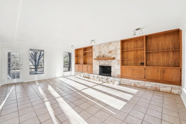 unfurnished living room featuring light tile patterned floors, built in features, and a stone fireplace