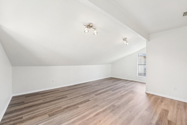 additional living space with wood-type flooring and vaulted ceiling with beams