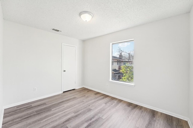 unfurnished room with a textured ceiling, light hardwood / wood-style flooring, and a healthy amount of sunlight