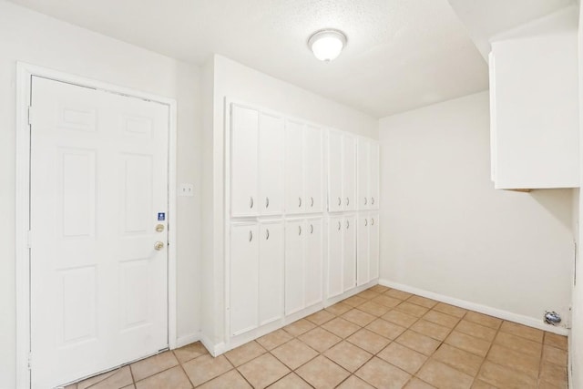 clothes washing area with light tile patterned flooring and a textured ceiling