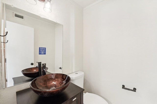 bathroom with crown molding, vanity, and toilet