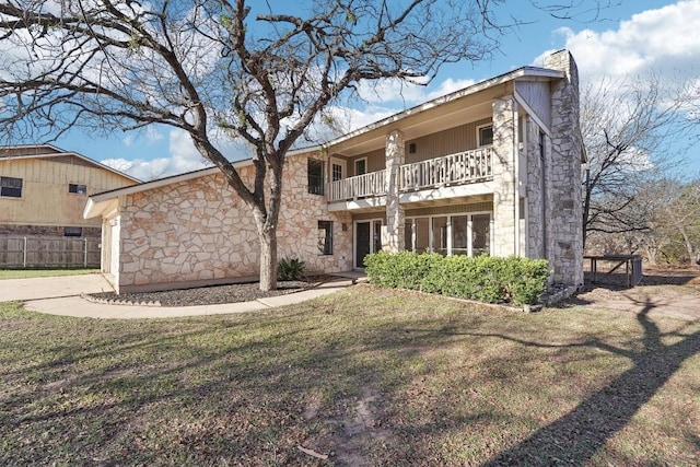 view of front of house with a balcony and a front lawn