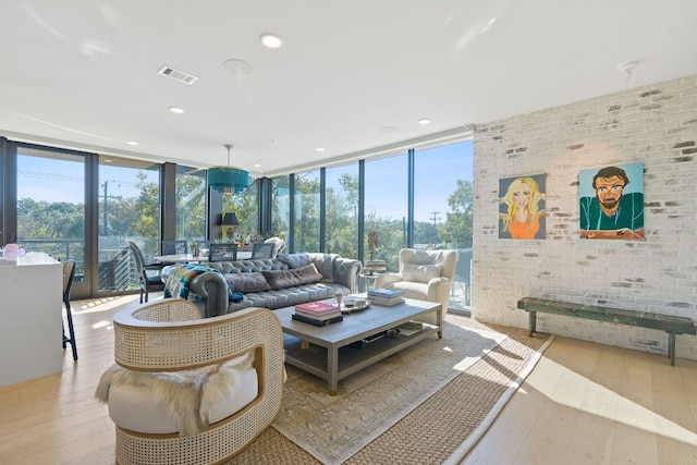 living room with light hardwood / wood-style flooring, floor to ceiling windows, and brick wall