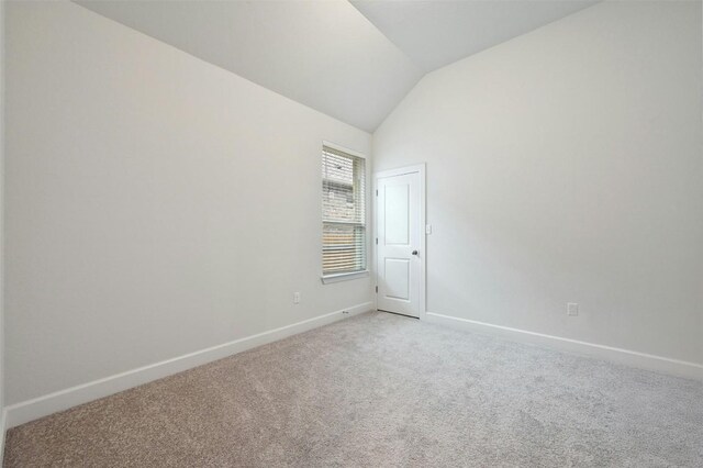 carpeted empty room featuring lofted ceiling