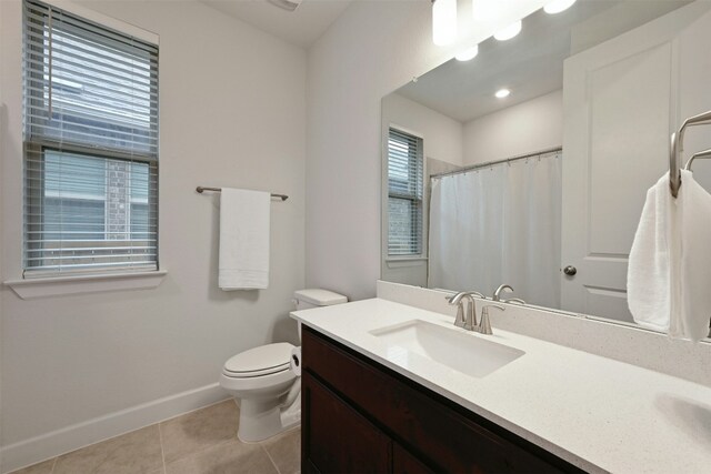 bathroom with tile patterned flooring, vanity, toilet, and a wealth of natural light