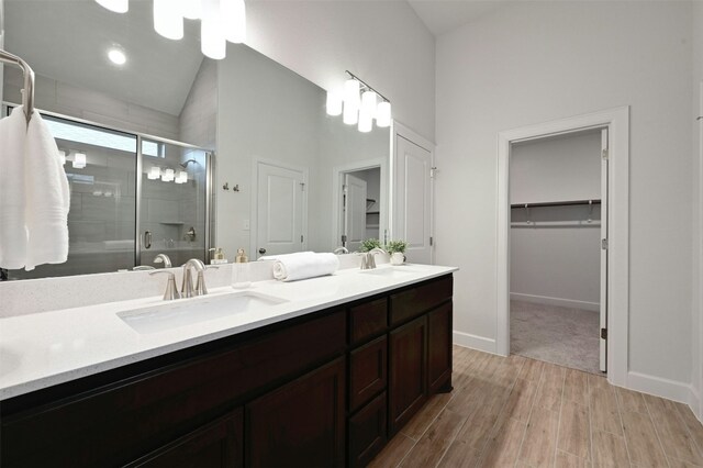 bathroom featuring vanity, a shower with shower door, and high vaulted ceiling