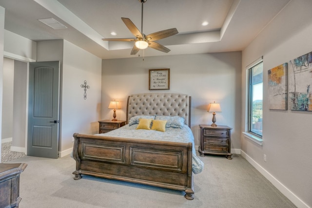 carpeted bedroom with ceiling fan and a raised ceiling