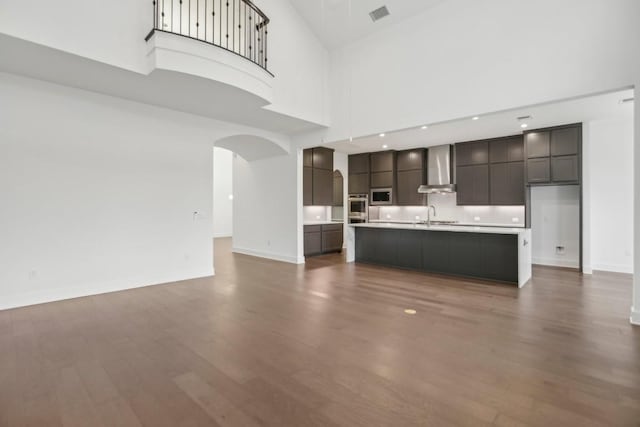 unfurnished living room with dark hardwood / wood-style floors, a towering ceiling, and sink