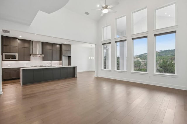 unfurnished living room featuring ceiling fan, sink, high vaulted ceiling, and hardwood / wood-style floors