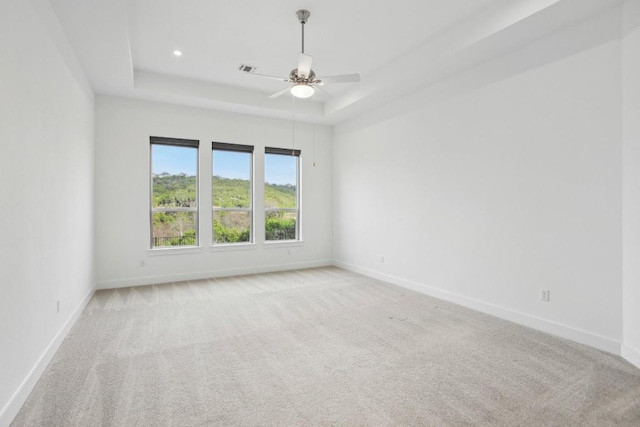 carpeted empty room featuring a raised ceiling and ceiling fan