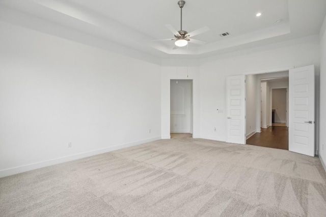 unfurnished bedroom with ceiling fan, a raised ceiling, and carpet floors