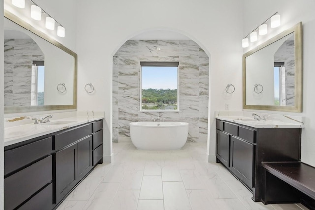 bathroom with a washtub, vanity, and tile walls