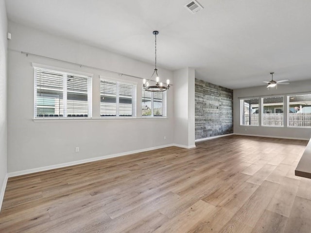 interior space with ceiling fan with notable chandelier and light wood-type flooring